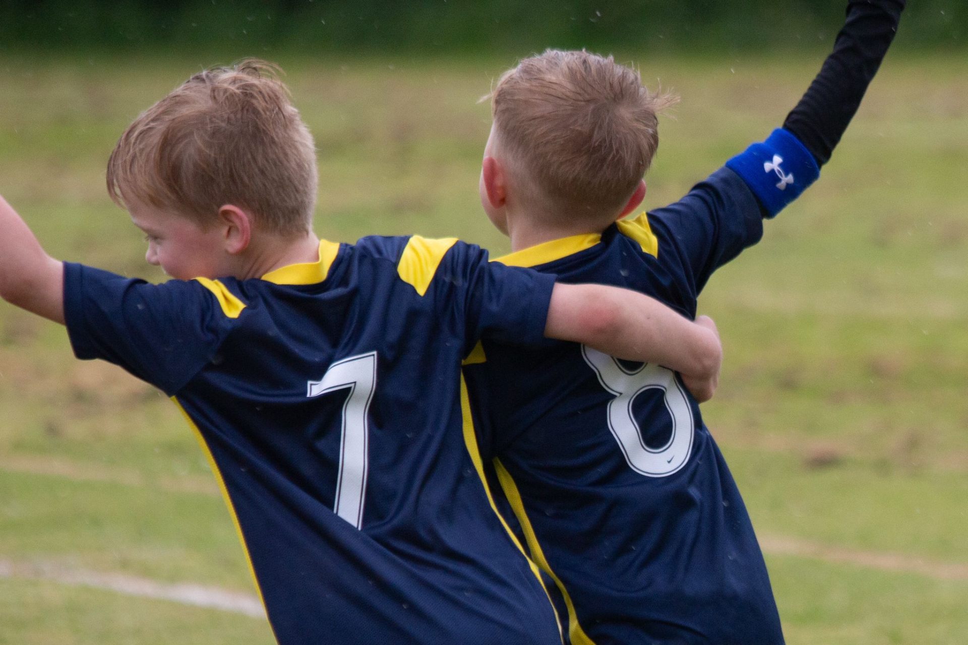 Two young Elton JFC players celebrating a goal, arms around each other
